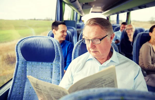 Счастливый пожилой человек, читающий газету в туристическом автобусе — стоковое фото