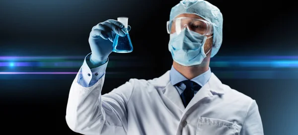 Cientista em máscara segurando frasco com produto químico — Fotografia de Stock