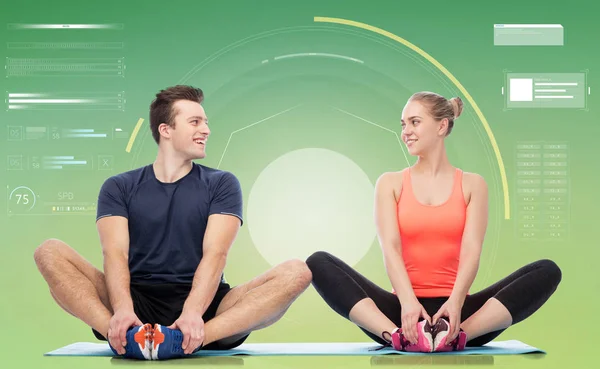 Happy sportive man and woman sitting on mats — Stock Photo, Image