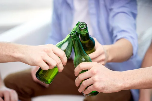 Close up of friends clinking beer bottles at home — Stock Photo, Image