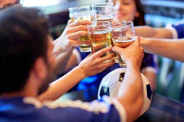 Aficionados al fútbol tintineo vasos de cerveza en el bar deportivo —  Fotos de Stock