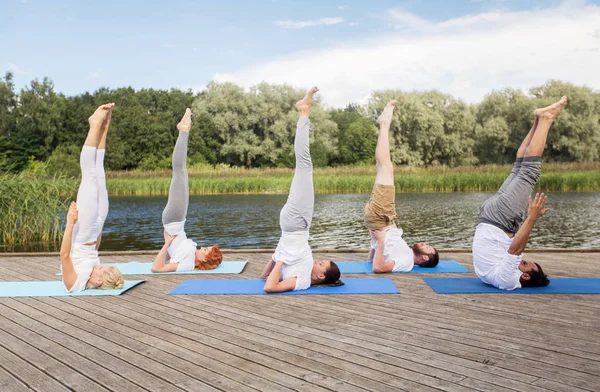 Personas haciendo yoga en hombrostand posan en la estera —  Fotos de Stock