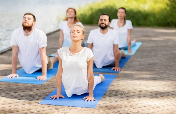 Grupo de pessoas fazendo exercícios de ioga ao ar livre — Fotografia de Stock