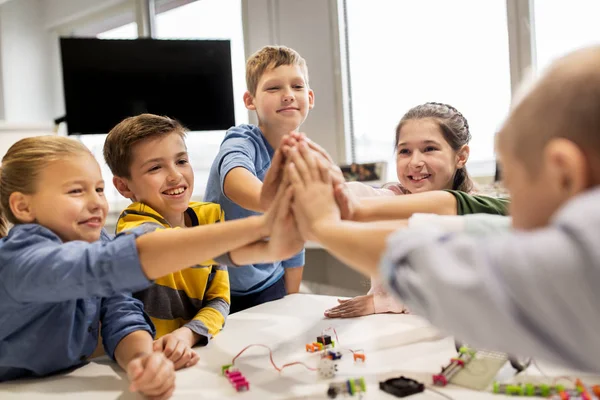 Glade børn gør high five på robotteknologi skole - Stock-foto