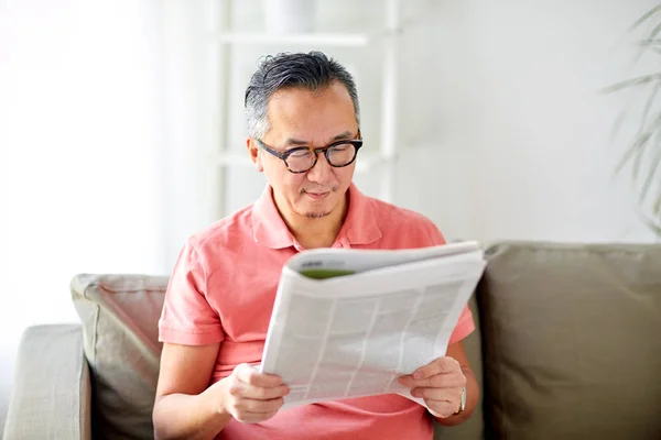 Hombre feliz en gafas leyendo el periódico en casa — Foto de Stock