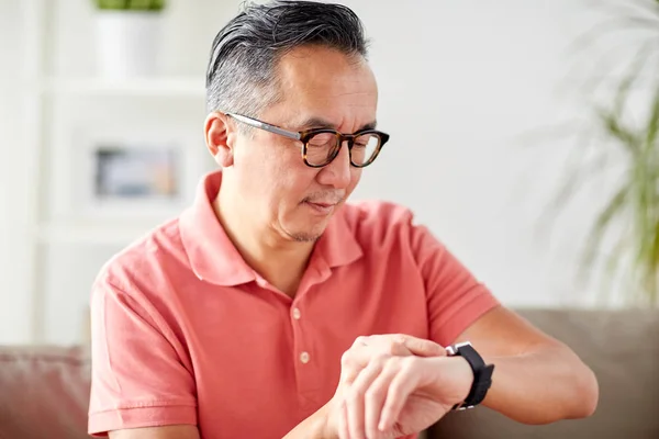 Ασιατική άνθρωπο ελέγχοντας την ώρα σε Ρολόι χεριού στο σπίτι — Φωτογραφία Αρχείου