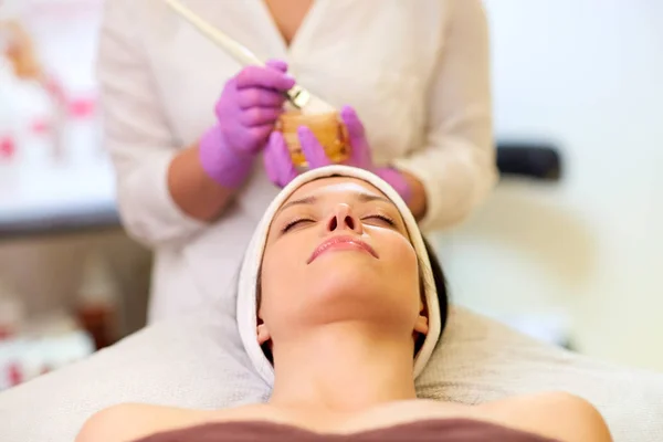 Kosmetikerin trägt Gesichtsmaske auf Frau im Wellnessbereich auf — Stockfoto