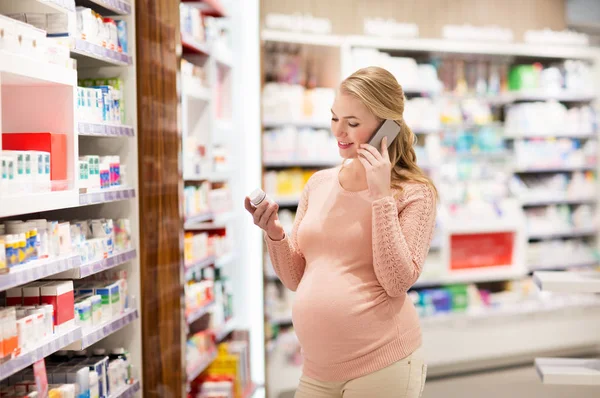 Mujer embarazada feliz con teléfono inteligente en la farmacia —  Fotos de Stock