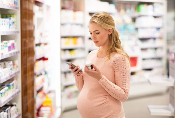 Gelukkig zwangere vrouw met medicatie bij apotheek — Stockfoto