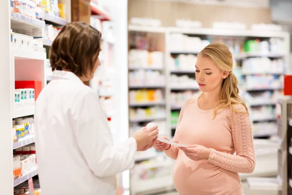 Mujer embarazada feliz y boticario en la farmacia — Foto de Stock