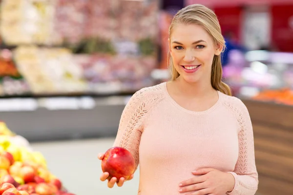 Szczęśliwy w ciąży kobieta z apple w sklepie spożywczym — Zdjęcie stockowe