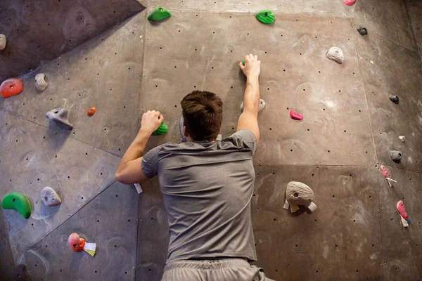 Jovem exercitando na parede do ginásio de escalada interior — Fotografia de Stock