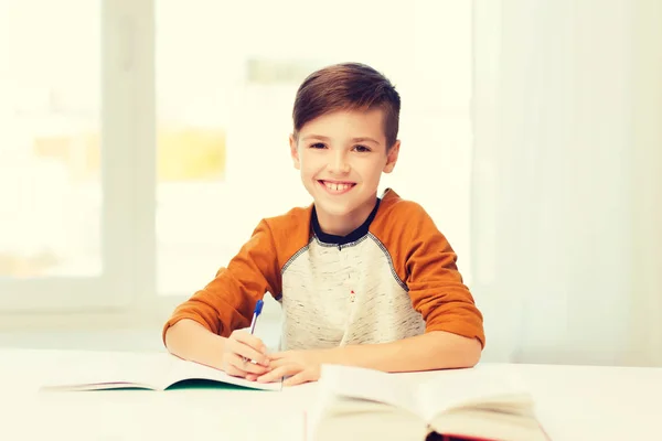 Uśmiechnięty uczeń piszący do notatnika w domu — Zdjęcie stockowe
