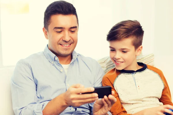 Счастливый отец и сын со смартфоном дома — стоковое фото