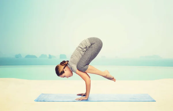 Mujer haciendo yoga en postura de grúa sobre estera —  Fotos de Stock