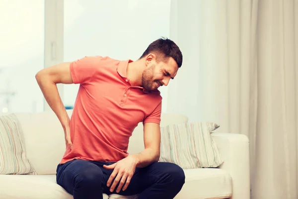 Hombre infeliz que sufre de dolor de espalda en casa —  Fotos de Stock