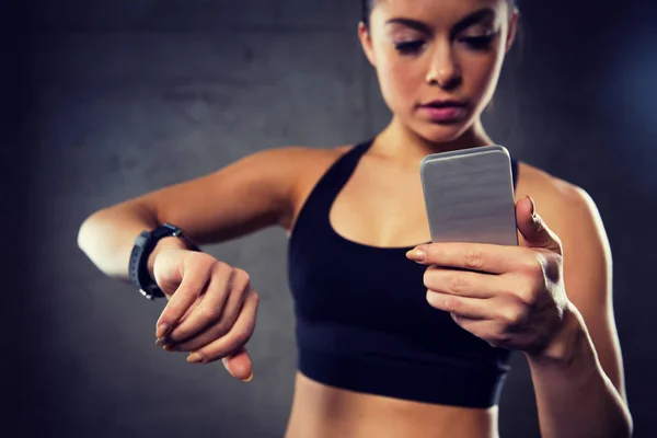 Frau mit Pulsuhr und Smartphone im Fitnessstudio — Stockfoto