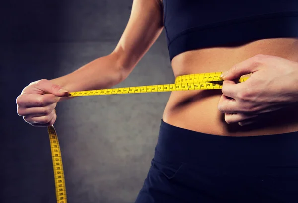 Primo piano della donna che misura la vita con il nastro in palestra — Foto Stock