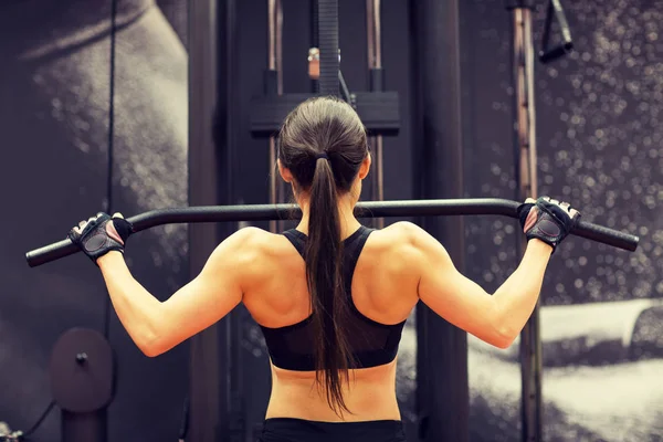 Kvinna som flexar muskler på kabel maskin i gymmet — Stockfoto