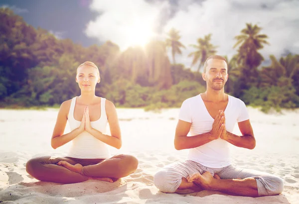 Gülümseyen çift sahilde yoga egzersizleri yapma — Stok fotoğraf