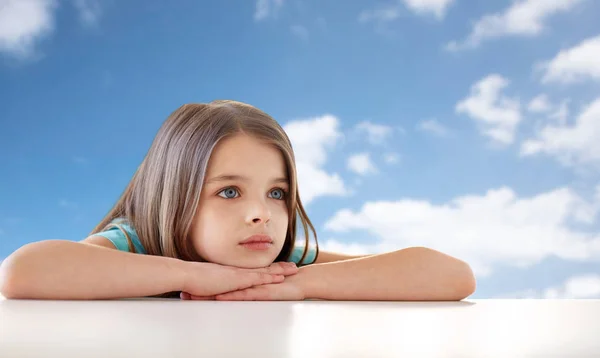 Mooi verdrietig meisje over blauwe lucht en de wolken — Stockfoto