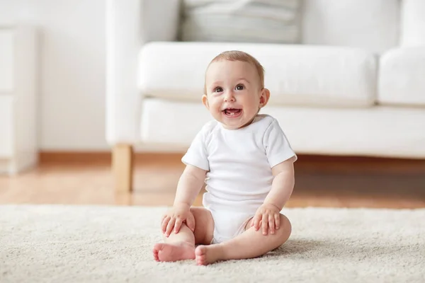 Boldog kisfiú vagy lány ül a padlón otthon — Stock Fotó