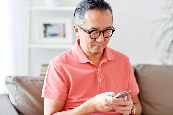 Homem com smartphone sentado no sofá em casa — Fotografia de Stock