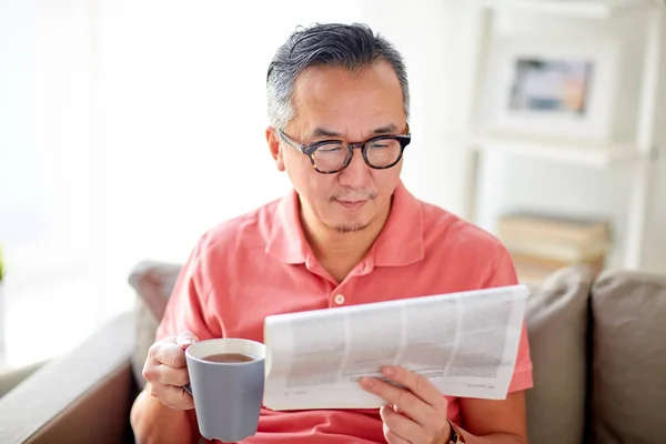 Mann trinkt Tee und liest Zeitung zu Hause — Stockfoto