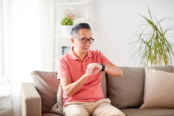 Azjatycki człowiek sprawdzanie czasu na zegarek w domu — Zdjęcie stockowe