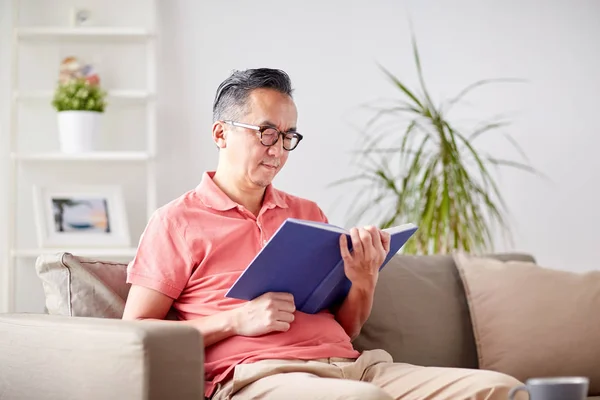 Чоловік сидить на дивані і читає книгу вдома — стокове фото