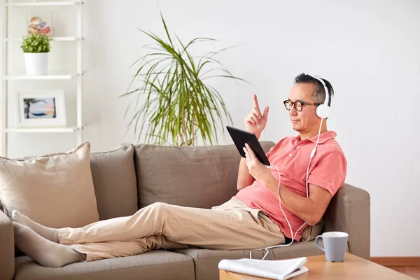 Homme avec tablette PC et écouteurs à la maison — Photo