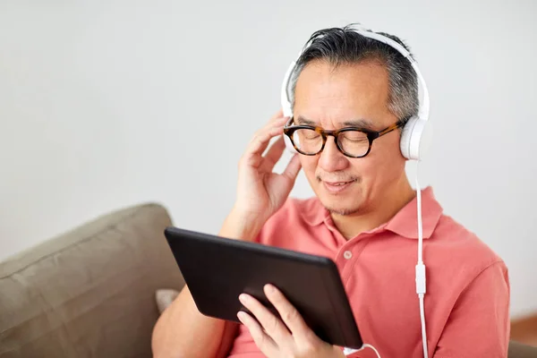 Homem com tablet pc e fones de ouvido em casa — Fotografia de Stock