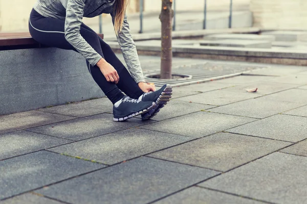 Крупним планом спортивна жінка зв'язує взуття на відкритому повітрі — стокове фото