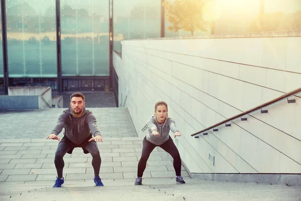 Couple doing squats on city street stairs — Stock Photo, Image