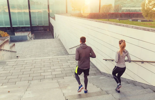 Couple running downstairs on city stairs — Stock Photo, Image