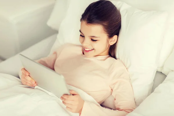 Gelukkig meisje liggend in bed met tablet pc thuis — Stockfoto