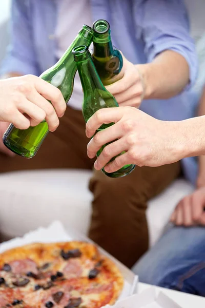 Close up of friends clinking beer bottles at home — Stock Photo, Image