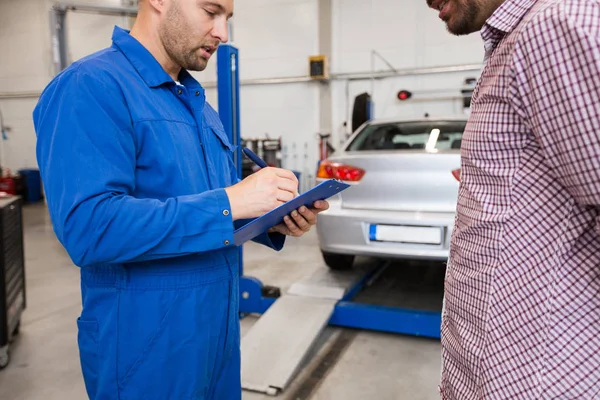 Automechaniker mit Klemmbrett und Mann im Autohaus — Stockfoto