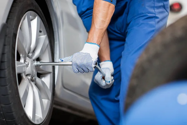 Mechanic with screwdriver changing car tire — Stock Photo, Image