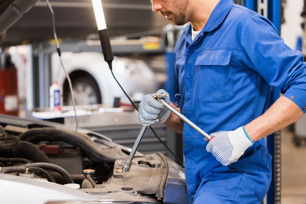 Monteur met moersleutel reparatie auto op de werkplaats — Stockfoto