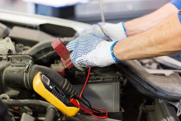 Auto mekaniker man med multimeter testa batteriet — Stockfoto