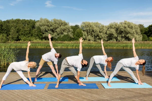 Mensen die yoga in linker driehoekje pose buitenshuis — Stockfoto