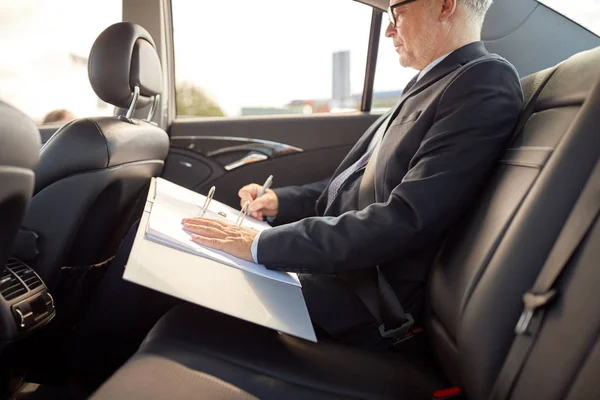Senior Geschäftsmann mit Papieren im Auto unterwegs lizenzfreie Stockfotos