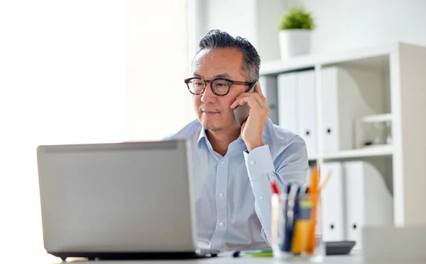 Affärsman med laptop uppmanar smartphone — Stockfoto