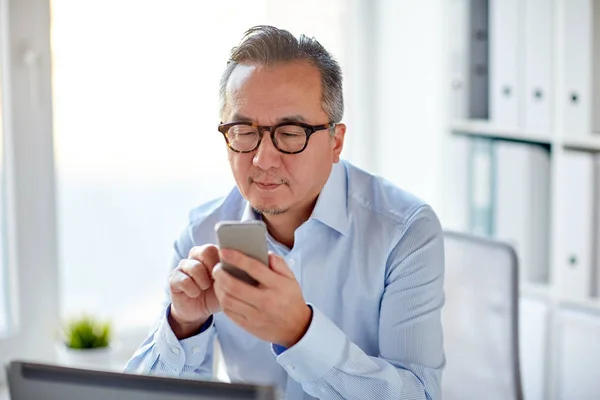 Affärsman med laptop textning på smartphone — Stockfoto