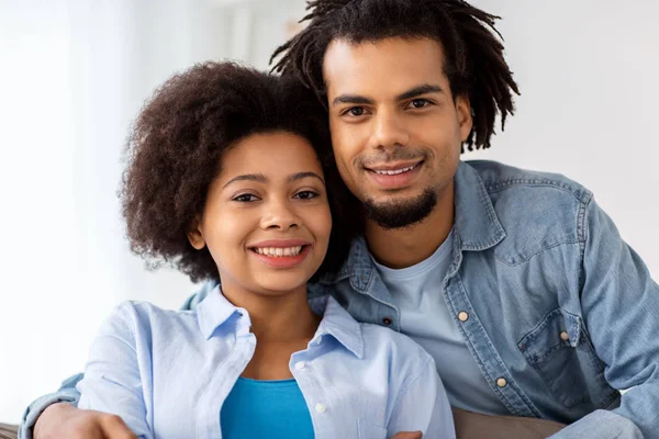 Feliz casal sentado no sofá e abraçando em casa — Fotografia de Stock