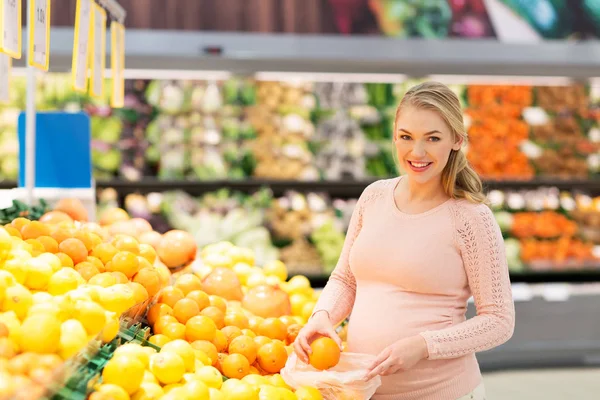 Kobieta w ciąży z torby zakup pomarańcze w grocery — Zdjęcie stockowe