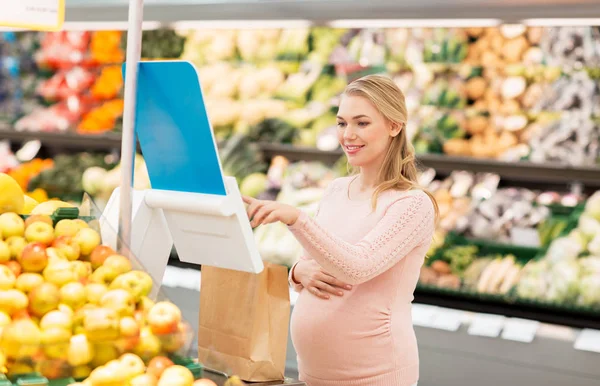 Mulher grávida com saco comprando pêras no supermercado — Fotografia de Stock