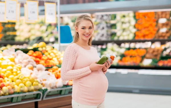 Mulher grávida feliz com suco no supermercado — Fotografia de Stock