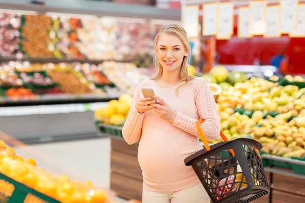 Schwangere mit Einkaufskorb und Smartphone — Stockfoto